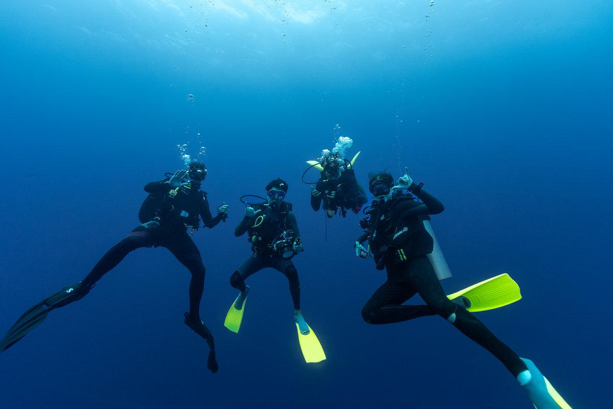 Group of scuba divers hovering in clear blue water during a dive