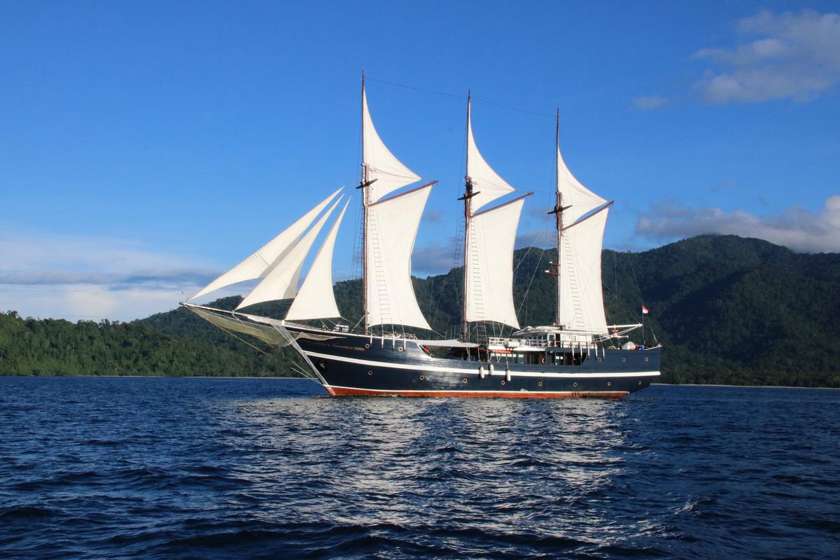 Dewi Nusantara traditional phinisi liveaboard under full sail near Raja Ampat, Indonesia